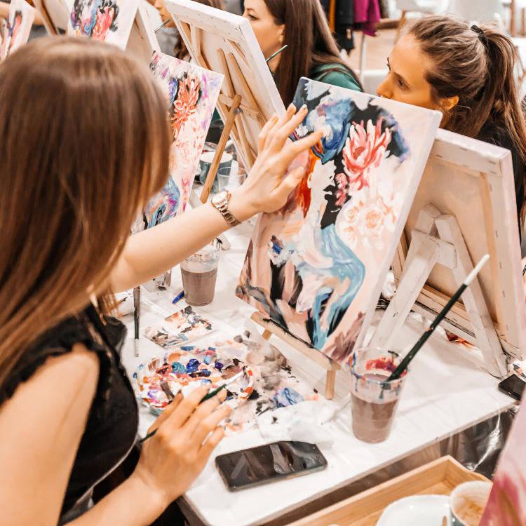  Young women paint with brushes on easels in art class. 